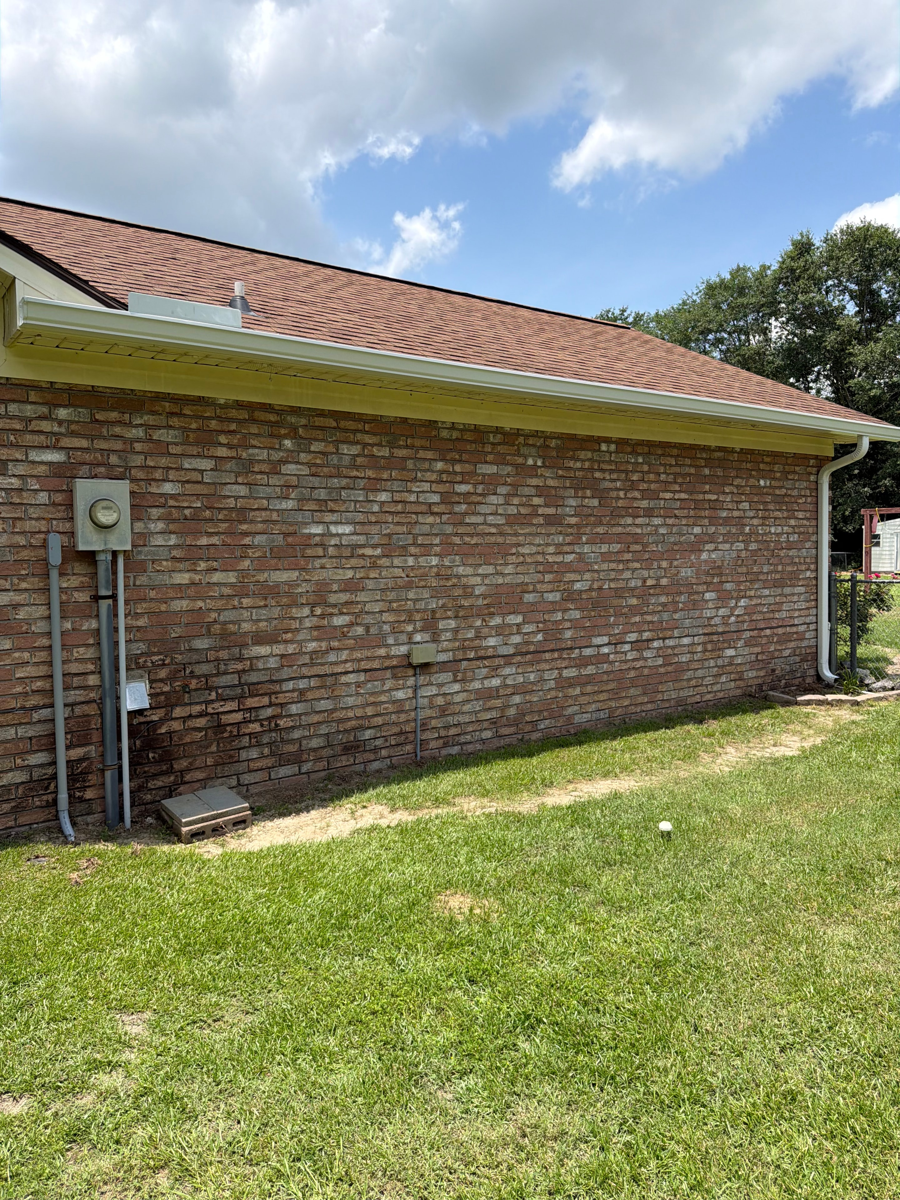 Gutter installation on brick home with green lawn
